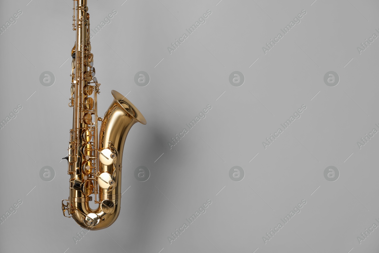 Photo of Golden saxophone on grey background. Space for text