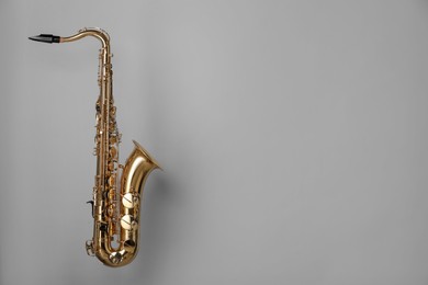 Photo of Golden saxophone on grey background. Space for text