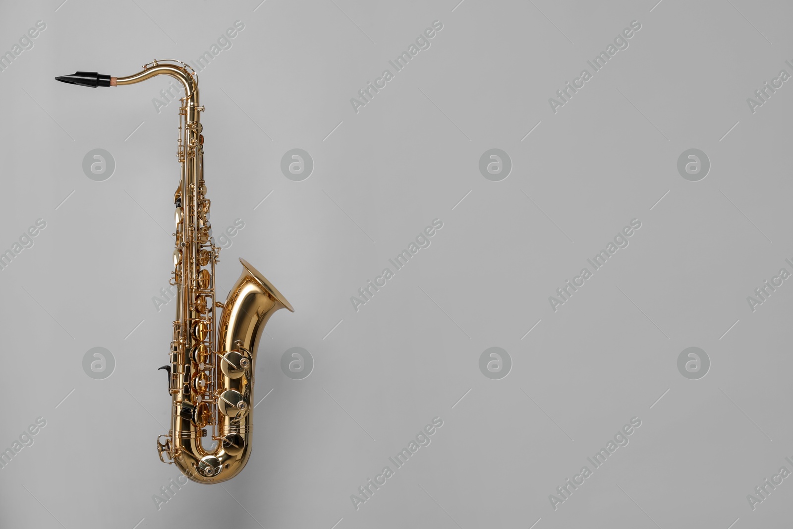 Photo of Golden saxophone on light grey background. Space for text