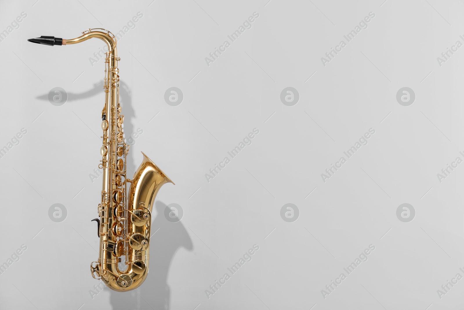 Photo of Golden saxophone on light grey background. Space for text