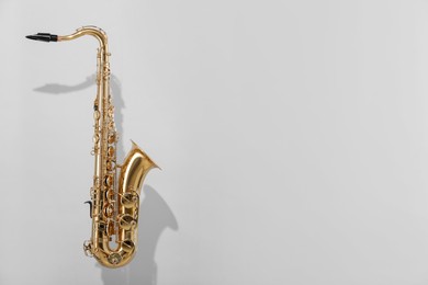 Photo of Golden saxophone on light grey background. Space for text