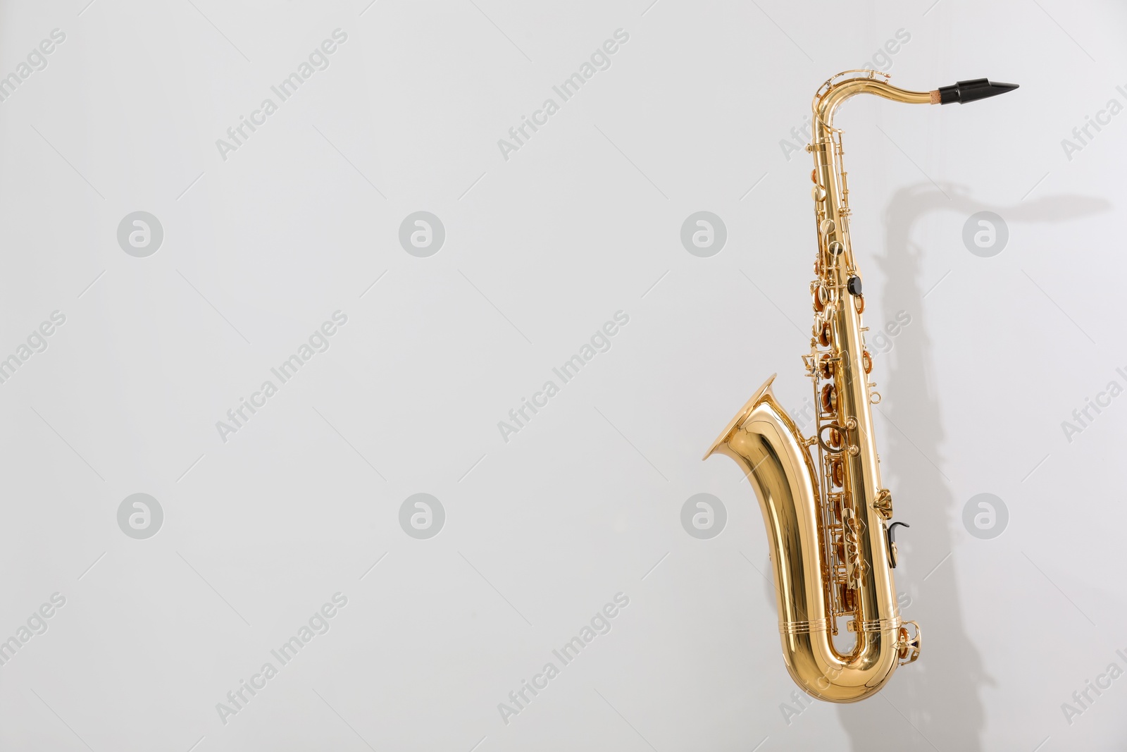 Photo of Golden saxophone on light grey background. Space for text