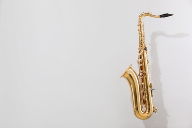 Photo of Golden saxophone on light grey background. Space for text