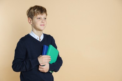 Photo of Portrait of teenage boy with books on beige background, space for text