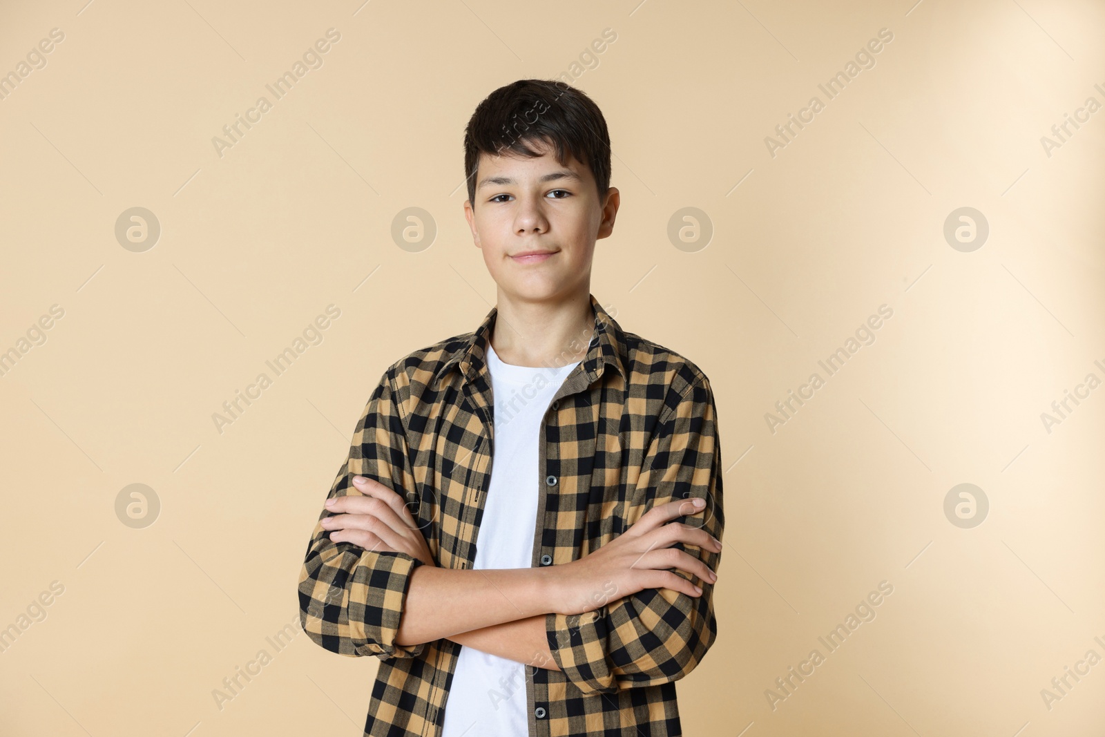 Photo of Portrait of teenage boy with crossed arms on beige background