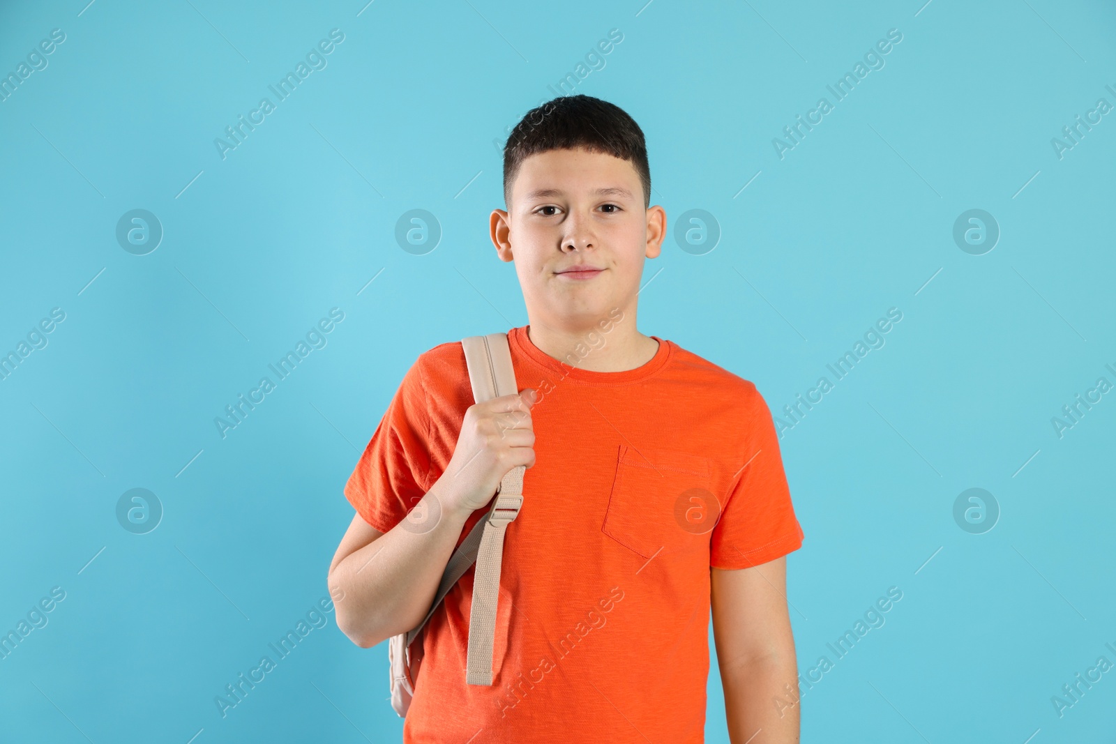 Photo of Portrait of teenage boy with backpack on light blue background