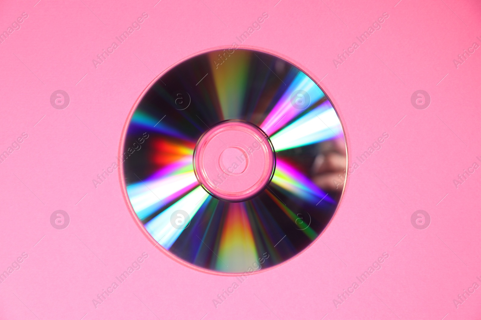 Photo of One shiny compact disc on pink background, top view