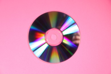 Photo of One shiny compact disc on pink background, top view