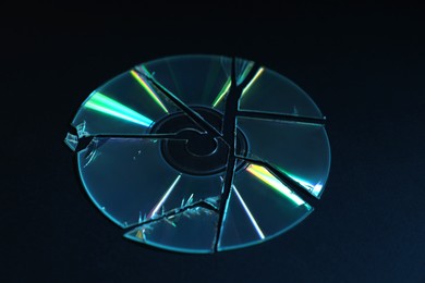 Photo of Broken compact disc on black background, closeup