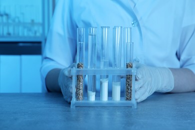 Photo of Laboratory testing. Scientist with test tubes of different samples at table indoors, closeup