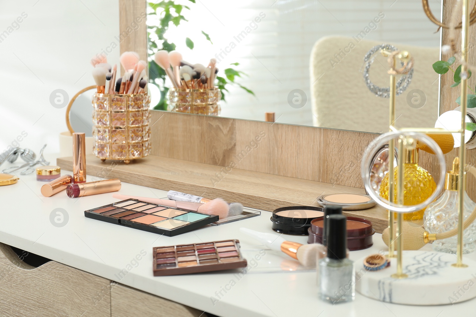 Photo of Makeup room. Dressing table with mirror, different beauty products and jewelry indoors