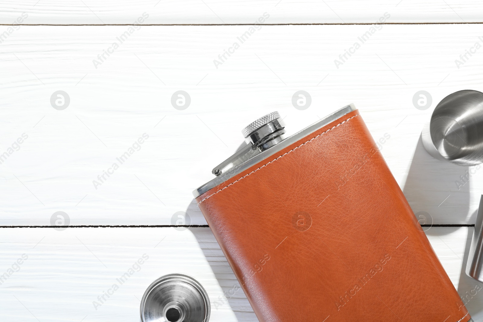 Photo of Hip flask, funnel and cup on white wooden table, flat lay. Space for text