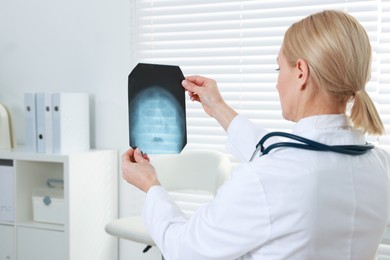 Photo of Doctor examining x-ray image of paranasal sinuses in clinic, space for text