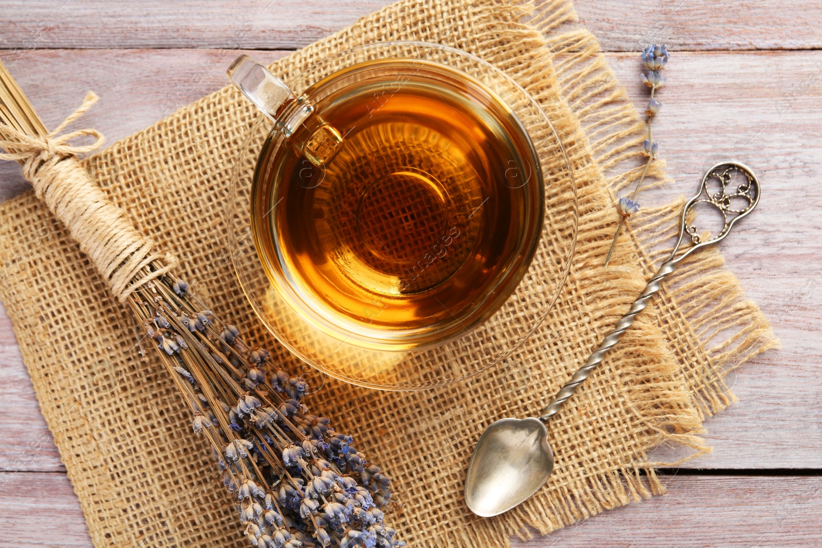 Aromatic lavender tea in glass cup, spoon and dry flowers on wooden table, flat lay Photo of Aromatic lavender tea in glass cup, spoon and dry flowers on wooden table, flat lay