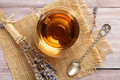 Photo of Aromatic lavender tea in glass cup, spoon and dry flowers on wooden table, flat lay