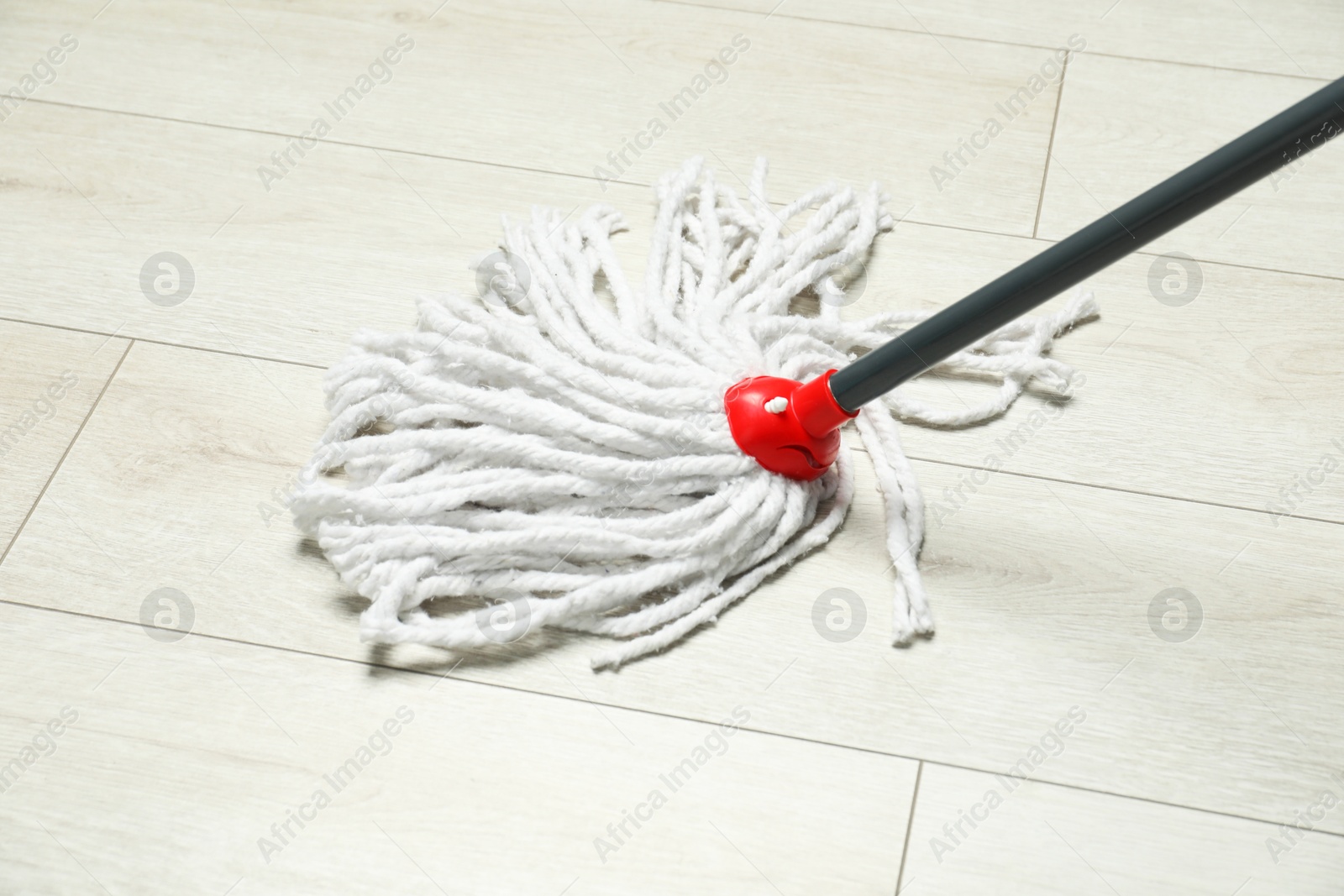 Photo of String mop on wooden floor. Cleaning equipment