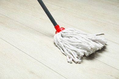 Photo of String mop on wooden floor. Cleaning equipment