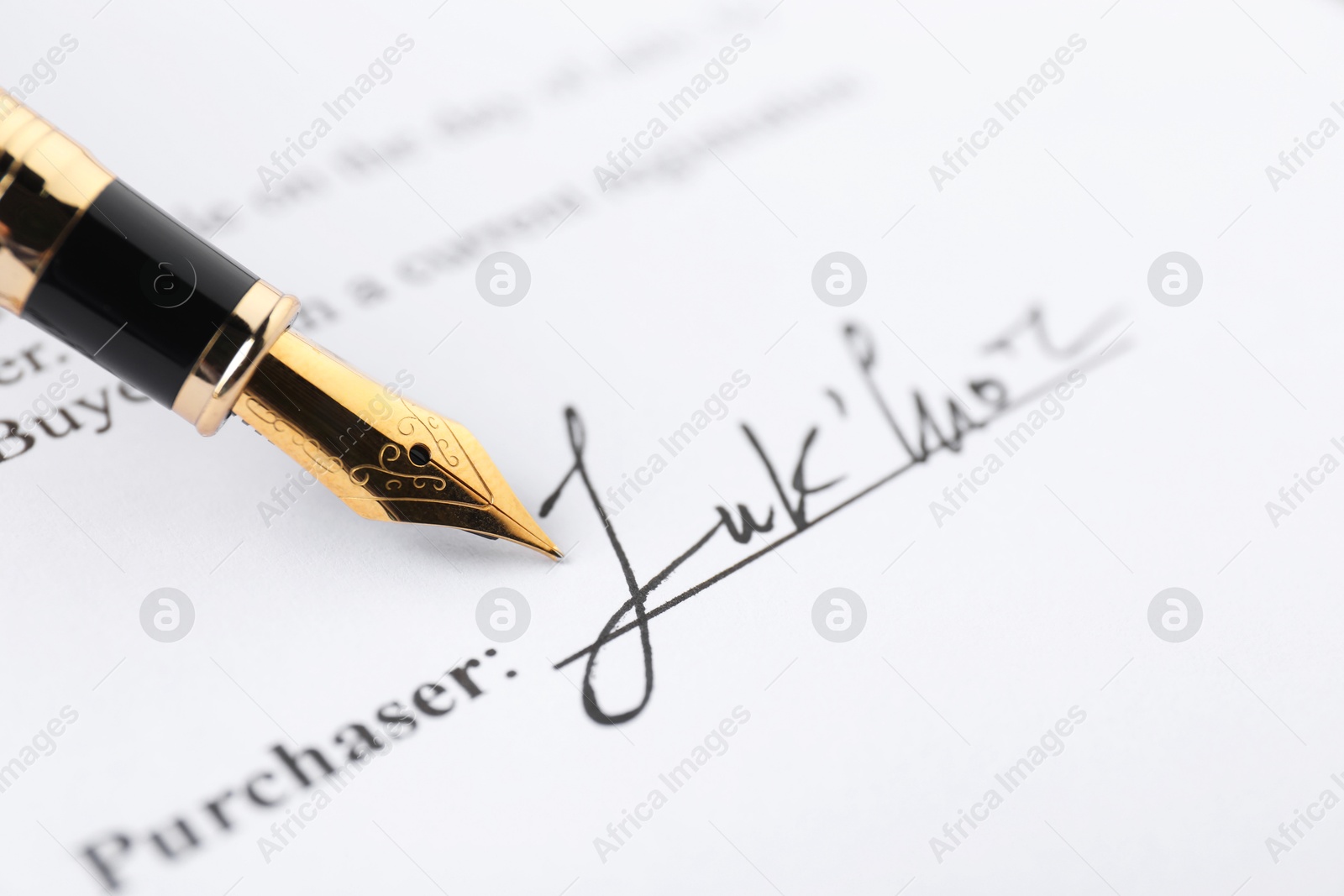 Photo of Signature and fountain pen on paperwork, closeup view