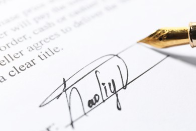 Photo of Fountain pen leaving signature on contract, closeup