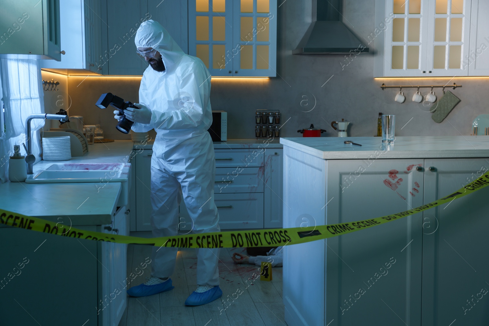 Photo of Forensic expert with camera working at crime scene in dark room