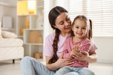 Photo of Family portrait of beautiful mother with little daughter at home. Space for text