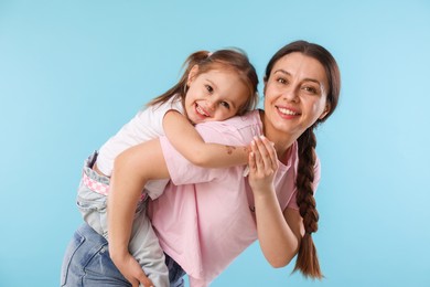 Photo of Portrait of happy mother with her cute daughter on light blue background