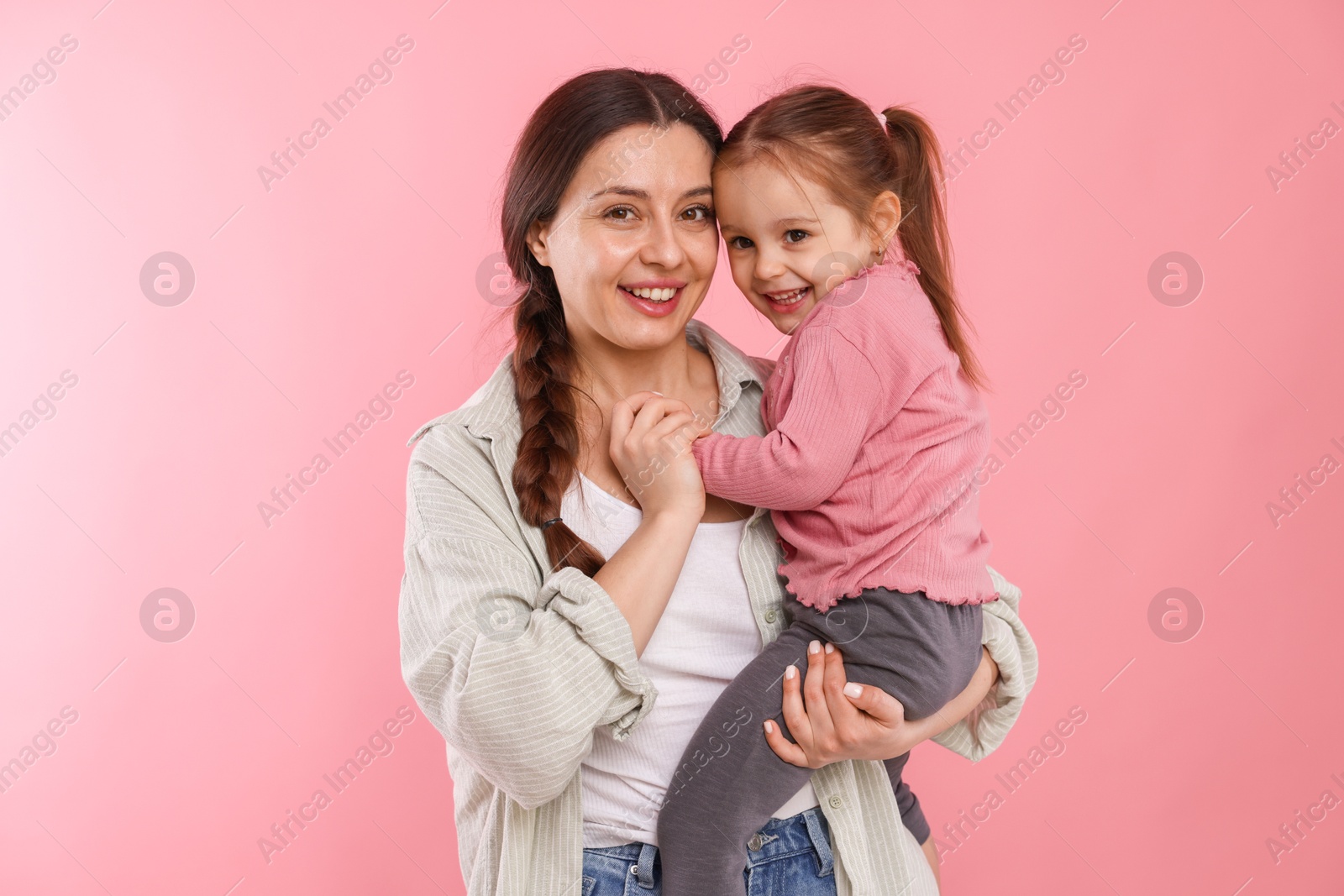 Photo of Portrait of happy mother with her cute daughter on pink background