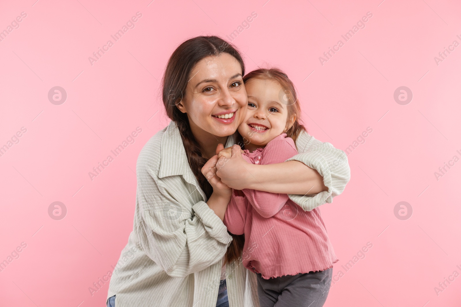 Photo of Portrait of happy mother and her cute daughter on pink background