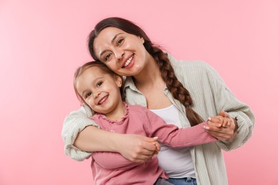 Family portrait of beautiful mother with little daughter on pink background