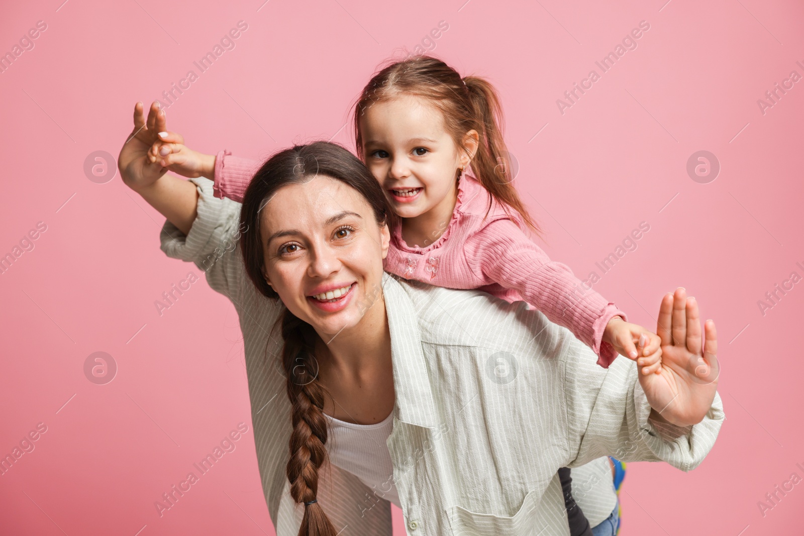 Photo of Portrait of happy mother and her cute daughter on pink background