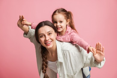 Photo of Portrait of happy mother and her cute daughter on pink background