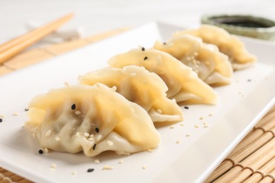 Photo of Delicious gyoza dumplings with sesame seeds served on table, closeup