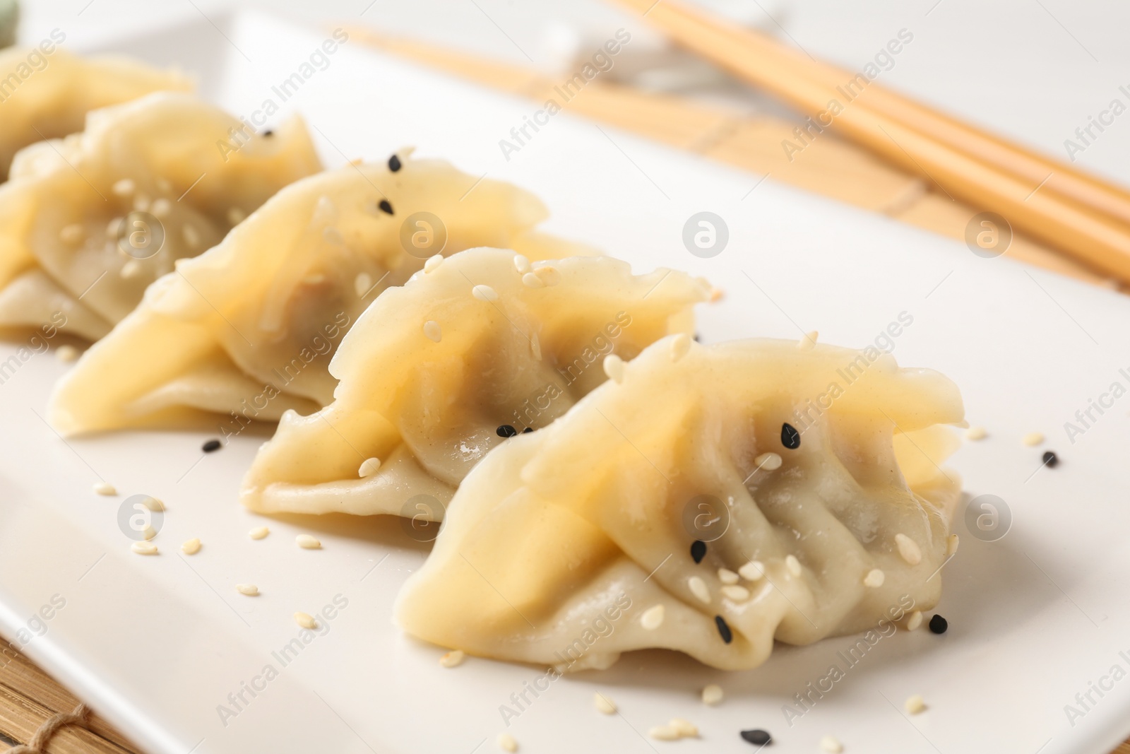 Photo of Delicious gyoza dumplings with sesame seeds served on table, closeup