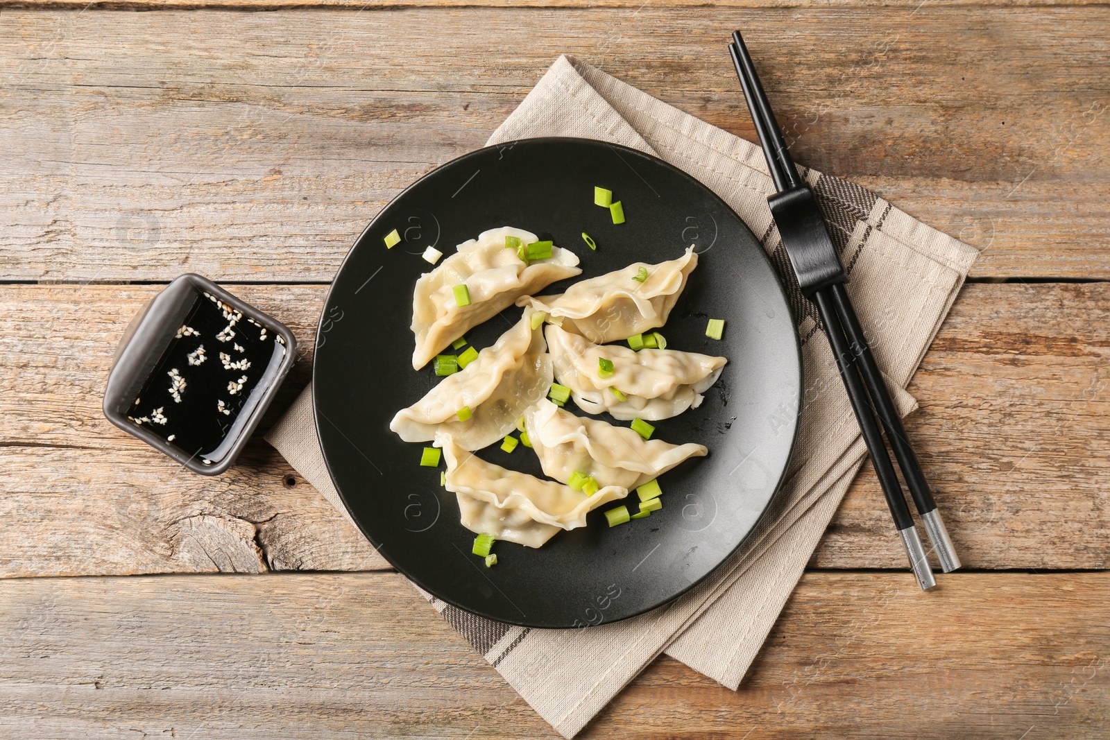 Photo of Delicious gyoza dumplings with chives served on wooden table, top view