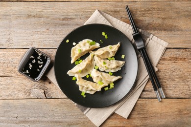 Photo of Delicious gyoza dumplings with chives served on wooden table, top view