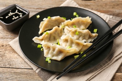 Photo of Delicious gyoza dumplings with chives served on wooden table, closeup