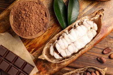 Photo of Cocoa pods with beans and chocolate on wooden table, flat lay