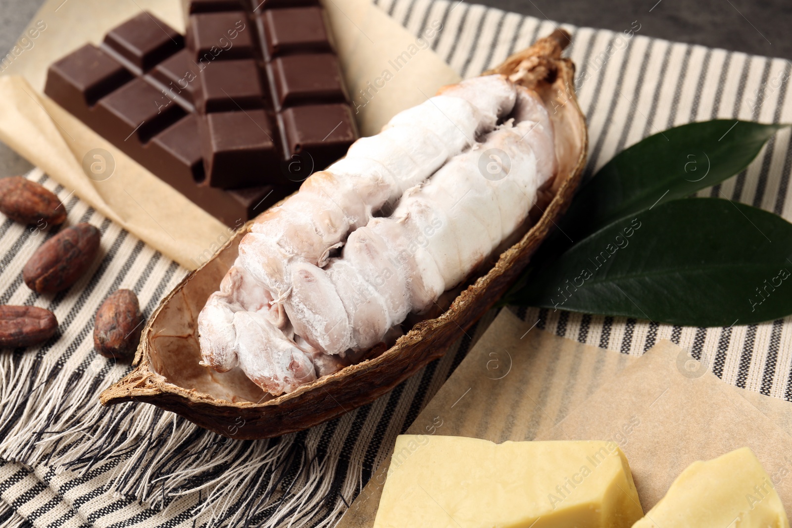 Cocoa pod with beans, butter and chocolate on table, closeup Photo of Cocoa pod with beans, butter and chocolate on table, closeup