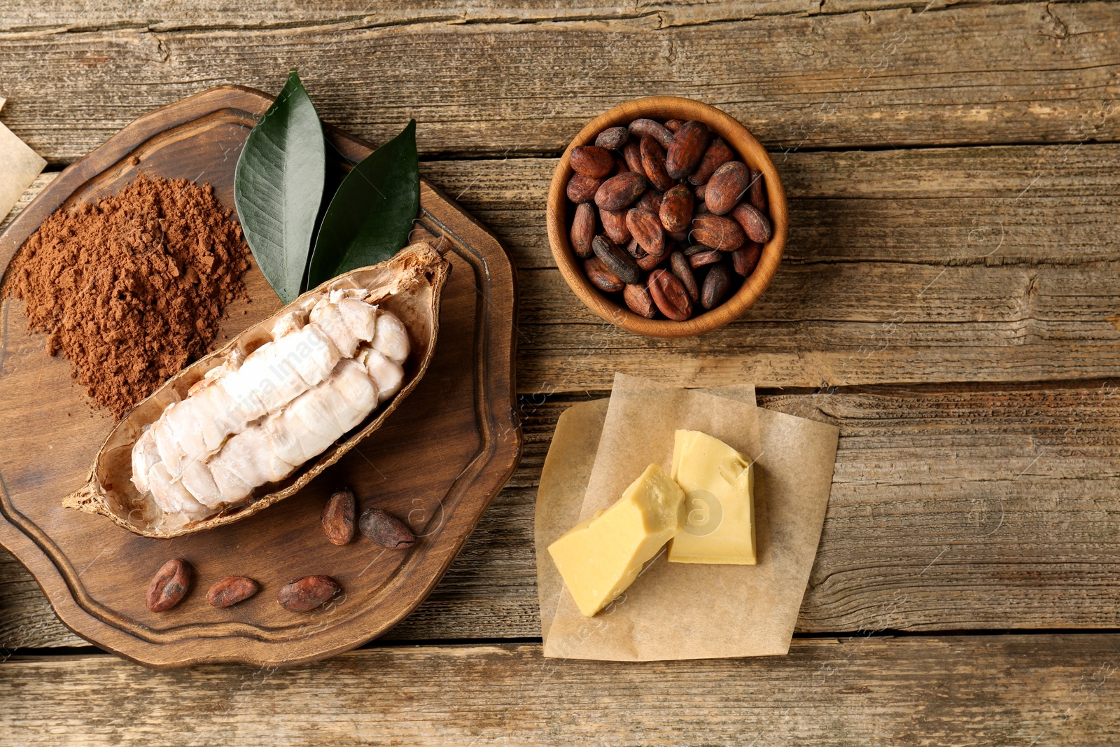 Cocoa pod with beans, powder and butter on wooden table, flat lay Photo of Cocoa pod with beans, powder and butter on wooden table, flat lay