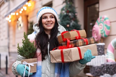 Photo of Happy woman with thuja tree and Christmas gifts on city street