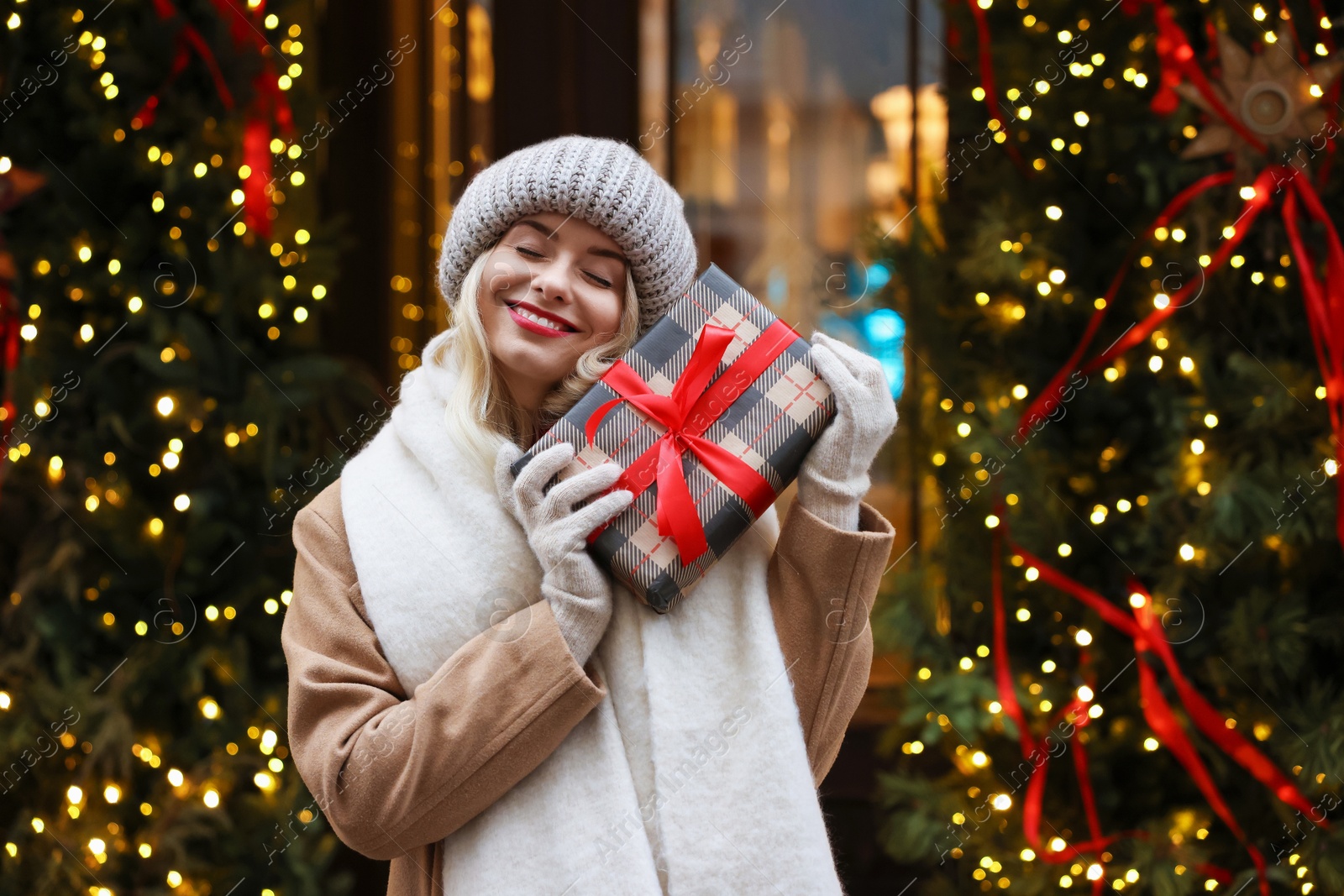 Photo of Happy woman with Christmas gift on city street