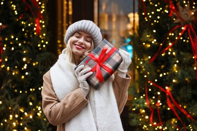 Happy woman with Christmas gift on city street