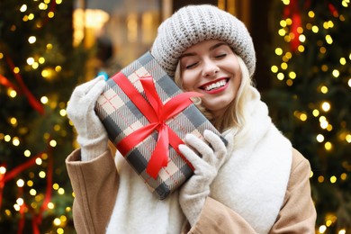 Photo of Happy woman with Christmas gift on city street