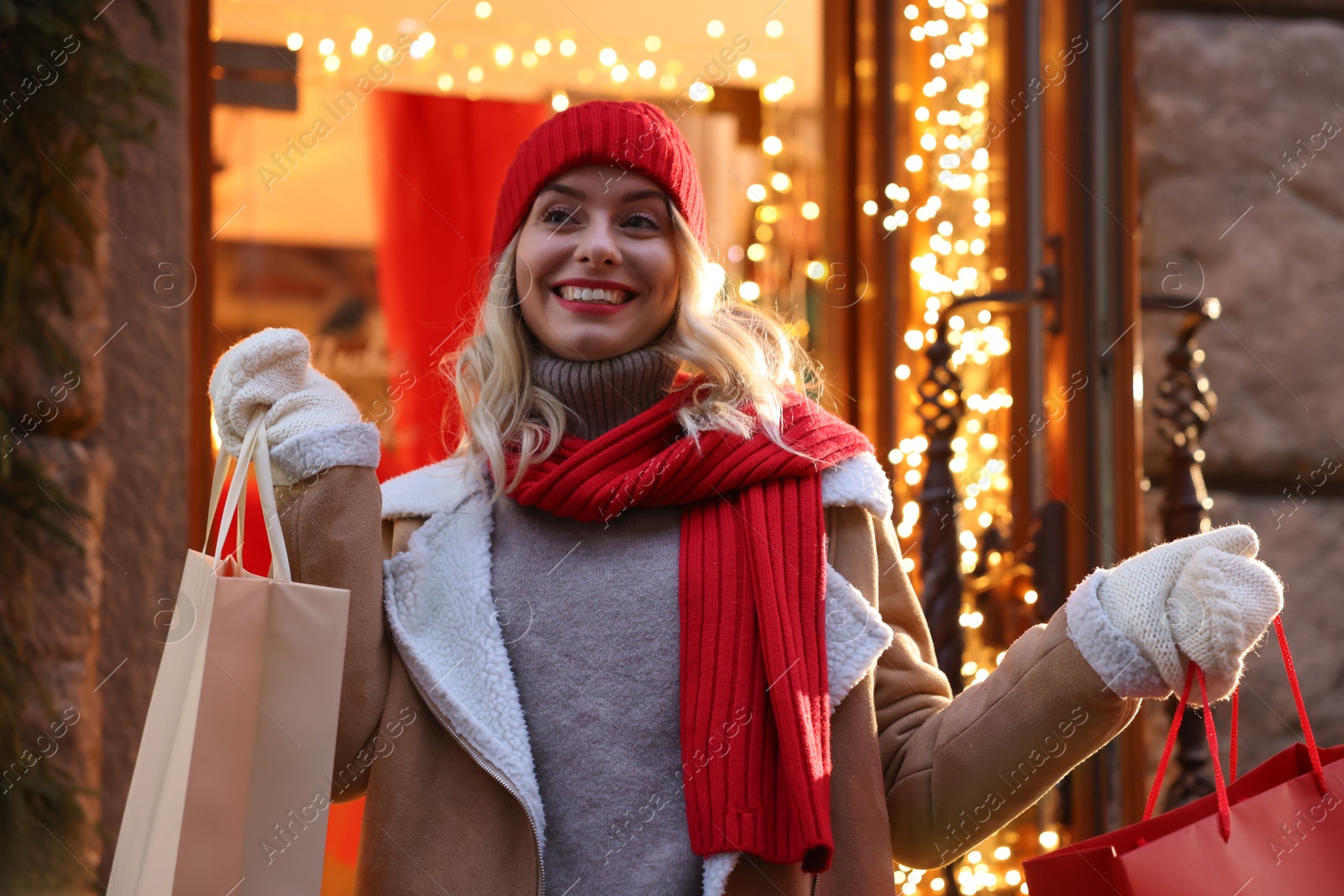 Photo of Happy woman with shopping bags on city street. Christmas season