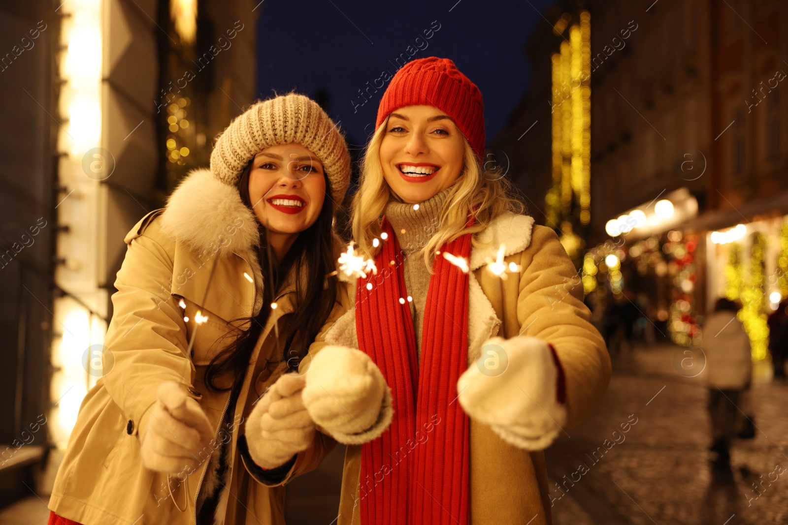 Photo of Happy friends with sparklers on city street. Christmas season