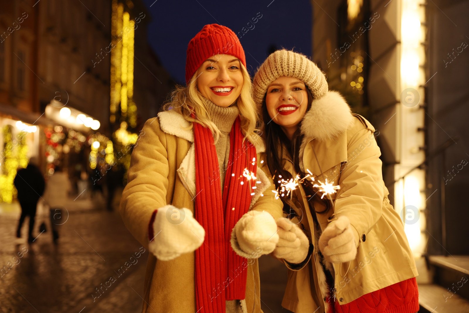 Photo of Happy friends with sparklers on city street. Christmas season