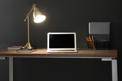 Photo of Home office. Comfortable workplace with laptop and lamp on wooden desk in room