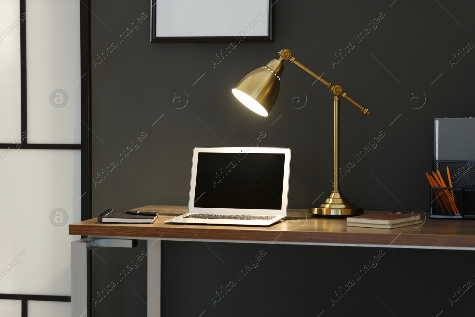 Home office. Comfortable workplace with laptop and lamp on wooden desk indoors Photo of Home office. Comfortable workplace with laptop and lamp on wooden desk indoors