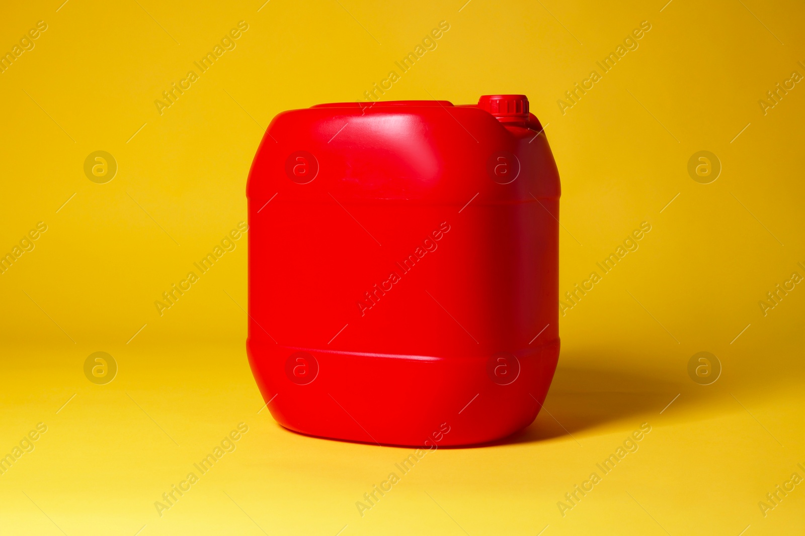 Photo of One red plastic canister on yellow background, space for text