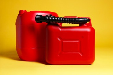 Photo of Two red plastic canisters on yellow background